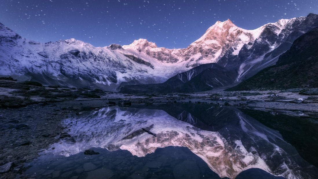 Starry night sky backdropping winter mountains